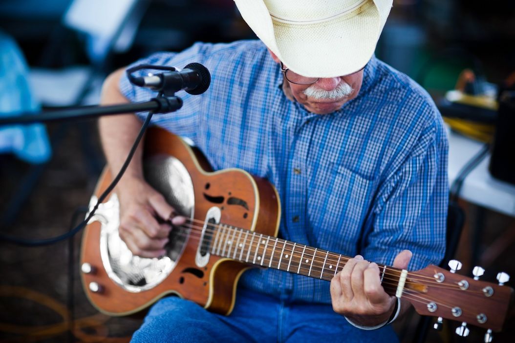 Mature man playing guitar by microphone.
