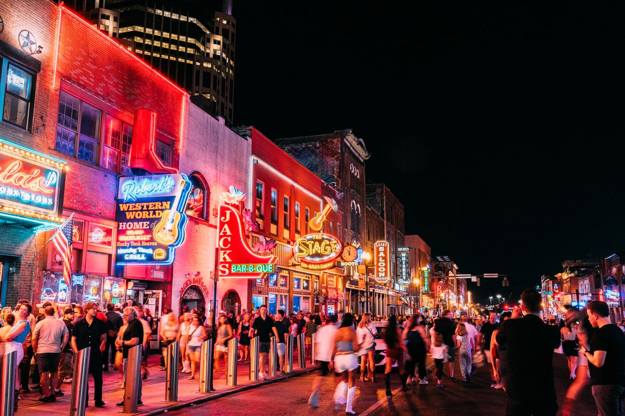Visitors exploring Broadway in downtown Nashville at night.