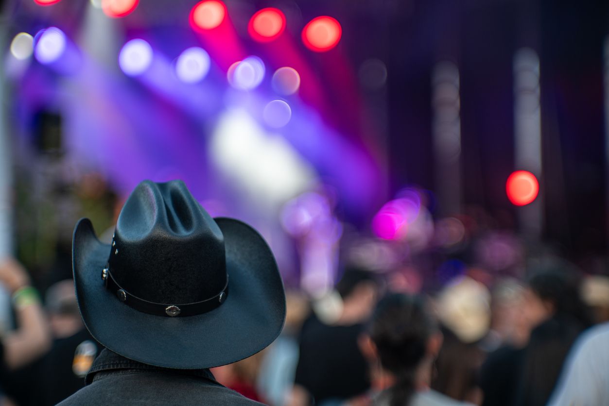 Audience member wearing a cowboy hat enjoying live music at a Nashville concert, capturing the spirit of Music City.