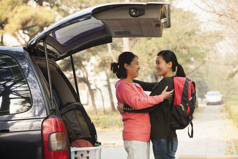 Mother and daughter on college move-in day near packed car, preparing to stay at a hotel near Nashville colleges.