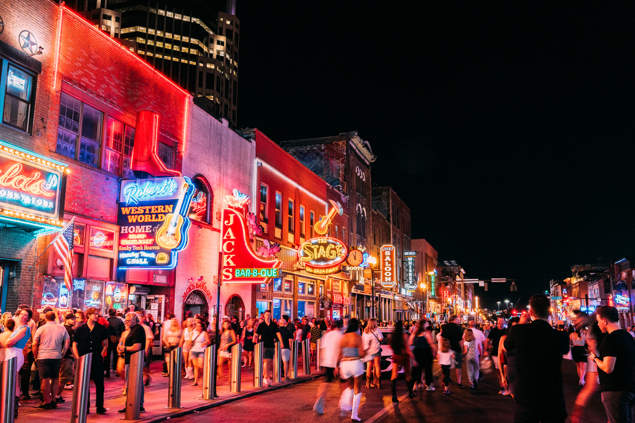 Visitors exploring Broadway in downtown Nashville at night.
